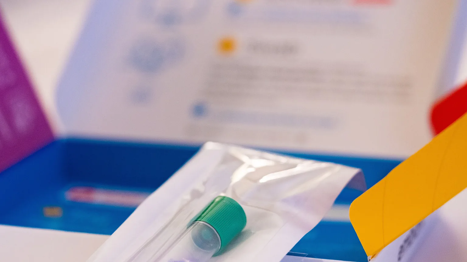 Tube de prélèvement salivaire sous sachet stérile dans la boîte ouverte d'un kit de test ADN à domicile